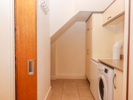 A laundry room with a washing machine and cabinets at Grange Cottage in Coldridge