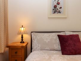 A bedroom with a bed, bedside table, lamp, and picture at Grange Cottage in Coldridge