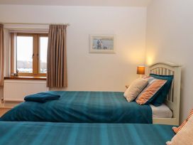 A bedroom with two beds and a window at Grange Cottage in Coldridge