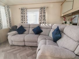 A living room featuring a sofa with cushions and curtains at CG 55