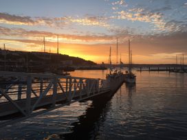 A sunset over water with boats at Rockfish Cottage in Brixham