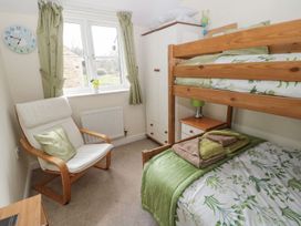 A bedroom with a bunk bed and armchair at Ramblers Cottage in Alnwick