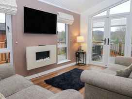 A living room with a television and fireplace at High Lake View Lodge White Cross Bay near Troutbeck Bridge
