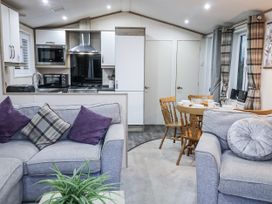 A living room with sofa and dining area at Lakeside Lodge in Stonham Aspal