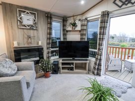 A living room with a television and seating area at Lakeside Lodge in Stonham Aspal