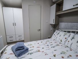 A bedroom with a bed and wardrobe at Lakeside Lodge in Stonham Aspal