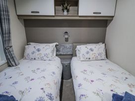 A bedroom with twin beds and a lamp at Lakeside Lodge in Stonham Aspal