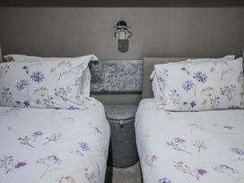 A bedroom with two beds and a bedside table at Lakeside Lodge in Stonham Aspal