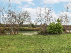 A view of a pond with grass and trees at Lakeside Lodge in Stonham Aspal