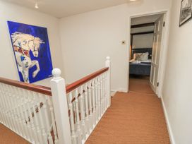 A hallway with a staircase and a painting at Ostlers in Burford