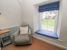 A snug with an armchair and a window at Ostlers in Burford