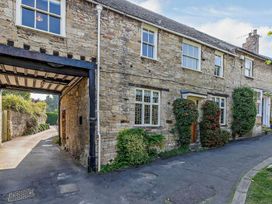 An outdoor view of a stone building with windows and plants at Ostlers Burford