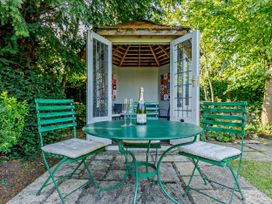 A table with chairs and a champagne bottle outside a shed at Ostlers Burford