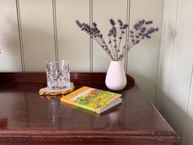 A table with a glass, vase with lavender, and a book at Cotswolds Farmhouse Cottage