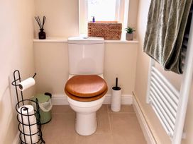 A toilet with a wooden seat and towel rail in a bathroom at Cotswolds Farmhouse Cottage