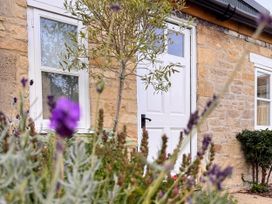 A door and window on a stone wall with flowers in the garden at Cotswolds Farmhouse Cottage