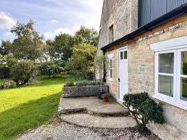 An outdoor view of a stone house with a pathway and planters at Cotswolds Farmhouse Cottage