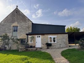 A house with a door and windows surrounded by grass at Cotswolds Farmhouse Cottage