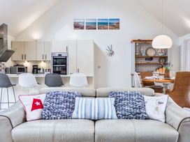 A living room with a sofa and kitchen in Beachcombers Marhamchurch