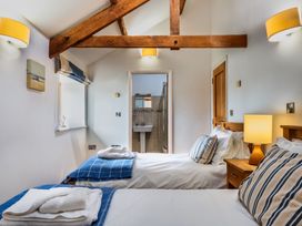 A bedroom with two beds and a bathroom visible at Woodyplatt in Marhamchurch