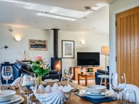 A living room with a television, sofa, and dining table at Chapel Park in Marhamchurch