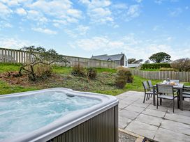 An outdoor area with a hot tub and dining set at Long Down Spa in Marhamchurch