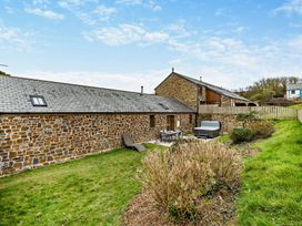 An outdoor area with a stone building and seating at Long Down Spa in Marhamchurch