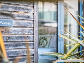 A wooden wall with a sign and glass door at Warrens Spa in Marhamchurch