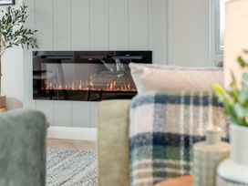 A living room with a fireplace and a plant at Trelowen 2.0 Spa Marhamchurch