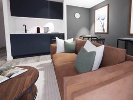 A living room with a sofa and kitchen area at Arvor Duplex 2.0 in Marhamchurch