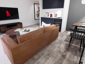 A living room with a tv, sofa, and kitchen counter at Arvor Duplex 2.0 in Marhamchurch