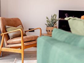 A living room with an armchair and a plant at Arvor Duplex 2.0 in Marhamchurch