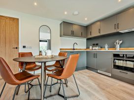 A kitchen with a dining table and chairs at Arvor Duplex 2.0 Marhamchurch
