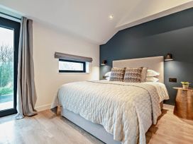 A bedroom with a bed and windows at Arvor Duplex 2.0 in Marhamchurch