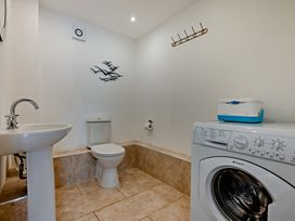A bathroom with a sink, toilet, and washing machine at Jack's House in Marhamchurch