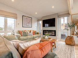 A living room with a sofa, television, and coffee table at Trelowen 4.0 Spa in Marhamchurch