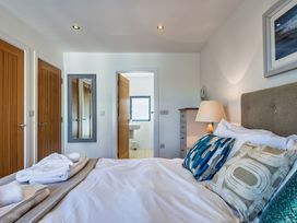 A bedroom with a bed and doors at Arundell in Marhamchurch