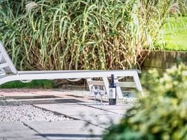 A lounge chair with a wine bottle and glasses on a patio at Arundell Marhamchurch