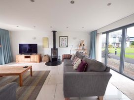 A living room with a television, sofa, and wood stove at Medlands in Marhamchurch