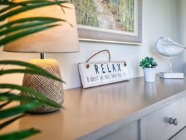 A side table with a lamp, a decorative sign, and a plant at Trevelyan in Marhamchurch