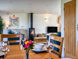 A dining room with a table and chairs and a fireplace at Trevelyan in Marhamchurch