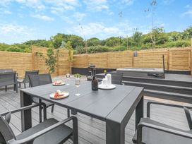An outdoor dining area with a table and hot tub at Gwari Spa Barn 3.0 in Marhamchurch