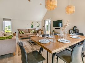 A living room with a sofa, dining area and television at Gwari Spa Barn 3.0, Marhamchurch