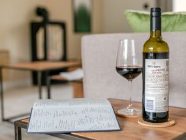 A wine bottle and glass with a menu on a table at Gwari Spa Barn 3.0 in Marhamchurch