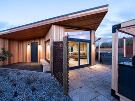 An exterior view of a modern wooden house with a hot tub at Trelowen 3.0 Spa in Marhamchurch