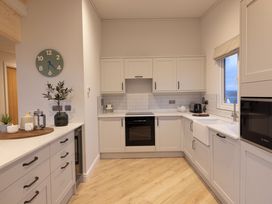 A kitchen with cabinets stovetop and sink at Trelowen 3.0 Spa in Marhamchurch