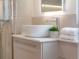 A bathroom with a sink, faucet, towels, and a plant at Trelowen 3.0 Spa, Marhamchurch