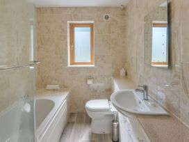 A bathroom with a bathtub, toilet, sink, and window at Windy Hills Spa in Marhamchurch
