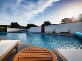 A swimming pool with sun loungers and a table at Windy Hills Spa in Marhamchurch