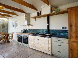 A kitchen with an oven and dining area at Whalesborough Farmhouse Spa in Marhamchurch
